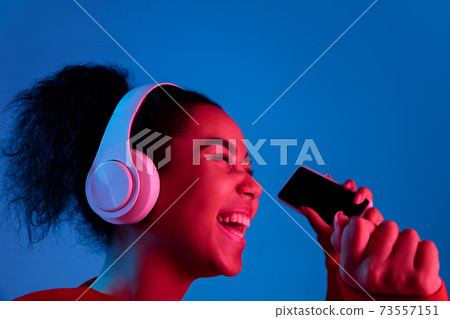 African-american woman's portrait isolated on blue studio background in multicolored neon light 73557151