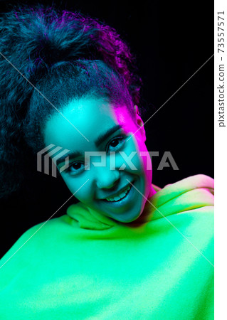 African-american woman's portrait isolated on dark studio background in multicolored neon light 73557571