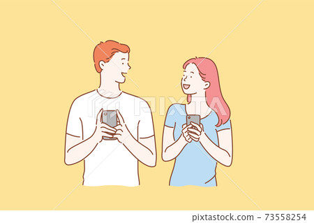 Concept of a young couple in love excited man and woman smiling. Boy and Girl meet or talk, both using mobile phones 73558254
