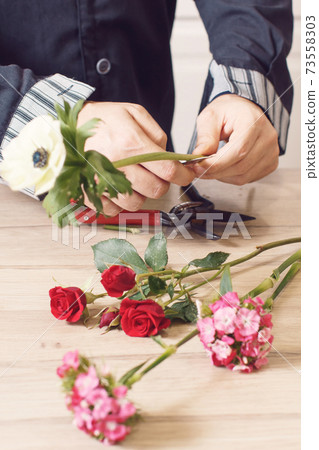Young male florist cutting a flowers at flower shop, close up 73558303