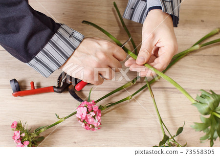 Young male florist cutting a flowers at flower shop, close up 73558305
