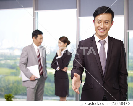 young confident asian business executive reaching out for a handshake 73558470