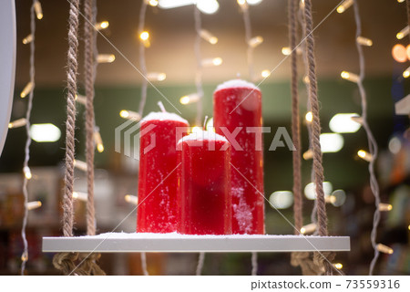 red candles on the stand, behind the garland 73559316