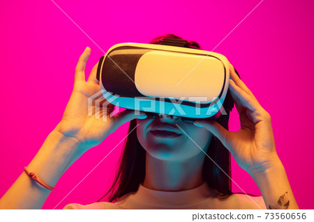 Caucasian beautiful woman's portrait isolated on pink studio background in multicolored neon light 73560656