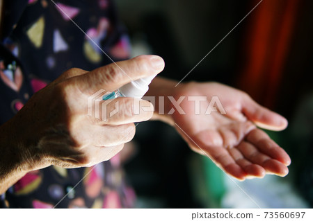 Hand of the elderly woman with alcohol spray bottle. Hand of the elderly woman with alcohol spray bottle. 73560697