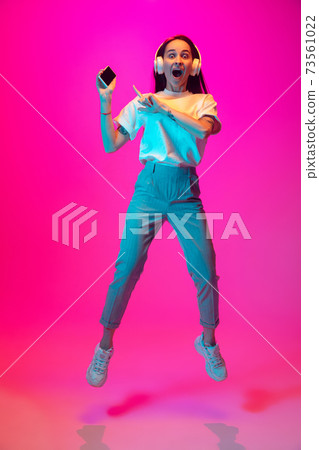 Caucasian beautiful woman's portrait isolated on pink studio background in multicolored neon light Caucasian beautiful woman's portrait isolated on pink studio background in multicolored neon light 73561022