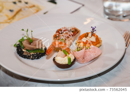 Served table for food and wine tasting. Snacks with shrimp, fish fillets, Spain tapas recipe food pintxos Served table for food and wine tasting. Snacks with shrimp, fish fillets, Spain tapas recipe food pintxos 73562045