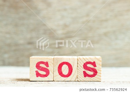 Alphabet letter block in word SOS (abbreviation of save our soul/ship or sibling over shoulder) on wood background 73562924