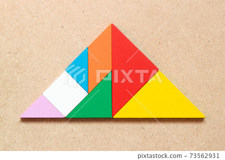 Color tangram puzzle in triangle shape on wood background Color tangram puzzle in triangle shape on wood background 73562931