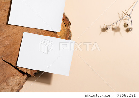 Blank white paper card on old wooden desk and beige background with flower Blank white paper card on old wooden desk and beige background with flower 73563281
