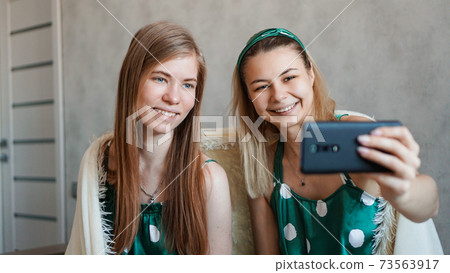 Beautiful happy girlfriends taking selfie with smartphone at pajama party Beautiful happy girlfriends taking selfie with smartphone at pajama party 73563917