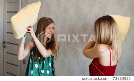 Two girl friends pillow fight in room 73563925