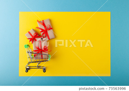 Gift box with red ribbon in mini grocery cart on pink background 73563996