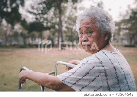 Asian senior or elderly old lady woman patient walk with walker in park with copy space, healthy strong medical concept 73564542