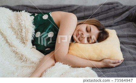 Beautiful young girl in a green nightie sleeps on a yellow pillow 73564947