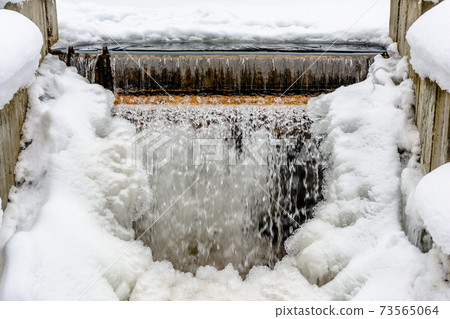 A small frozen waterfall, cold water, snow and ice, winter and frost. A small frozen waterfall, cold water, snow and ice, winter and frost. 73565064