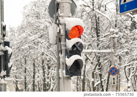 A working traffic light on a city street in winter.The red light of the traffic light is on A working traffic light on a city street in winter.The red light of the traffic light is on 73565730