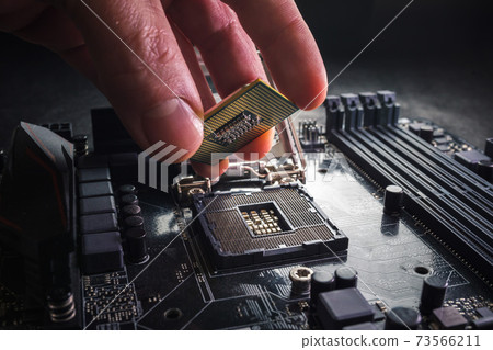 Technician plug in CPU microprocessor to motherboard socket. Workshop background. PC upgrade or repair concept. 73566211
