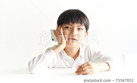 Elementary school boy talking on a smartphone Elementary school boy talking on a smartphone 73567052