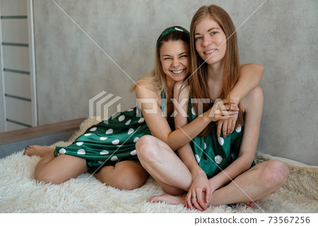 Lifestyle, friendship concept - two beautiful girls dressed in pajamas hugging Lifestyle, friendship concept - two beautiful girls dressed in pajamas hugging 73567256