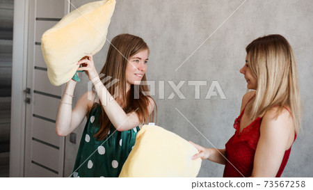Two girl friends pillow fight in room 73567258