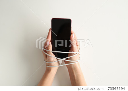 Hands are tied with wire and hold smartphone 73567394