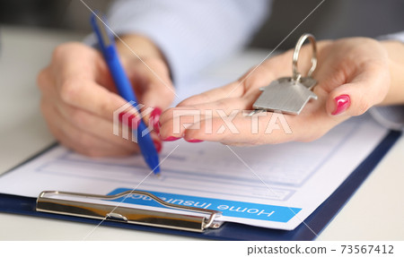 Female hands hold house keys and fill out real estate insurance Female hands hold house keys and fill out real estate insurance 73567412
