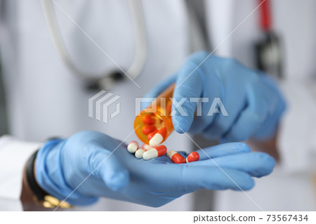 Doctor sprinkles the pills on gloved hand 73567434
