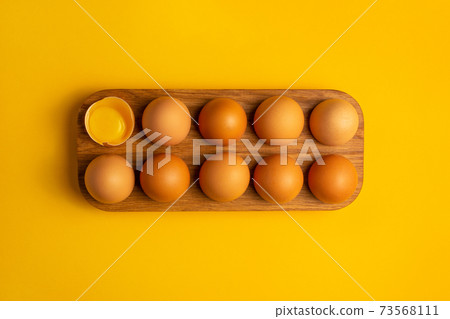 Tray with dozen eggs on yellow background Tray with dozen eggs on yellow background 73568111