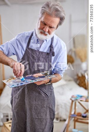 senior grey haired artist man painting using painter palette senior grey haired artist man painting using painter palette 73568195