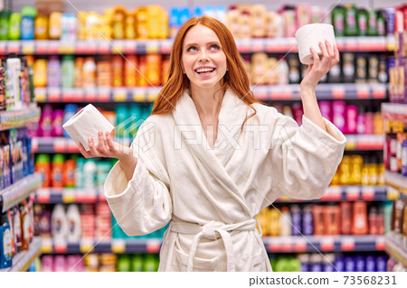 funny caucasian woman with red hair choosing the best toilet paper 73568231