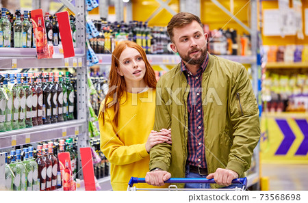 portrait of caucasian couple in the department of alcohol in supermarket 73568698