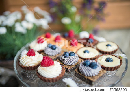 Selection of colorful and delicious cake desserts on tray on table. 73568803