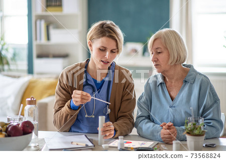 Caregiver or healthcare worker with senior woman patient, explaining how to use litmus paper. Caregiver or healthcare worker with senior woman patient, explaining how to use litmus paper. 73568824