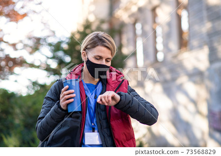 Woman caregiver, nurse or healthcare worker outdoors on the way to work, coronavirus concept. 73568829