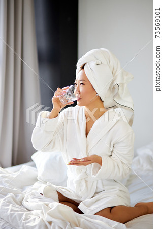healthy young asian woman taking pills and a glass of water for treatment 73569101