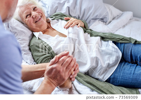 loving mature man supporting his sick wife lying on bed loving mature man supporting his sick wife lying on bed 73569309