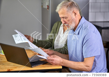 caucasian mature couple checking bills while managing accounts on home banking app caucasian mature couple checking bills while managing accounts on home banking app 73569369