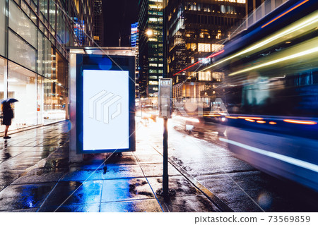 Bus station billboard in rainy night with blank copy space screen for advertising or promotional content Bus station billboard in rainy night with blank copy space screen for advertising or promotional content 73569859
