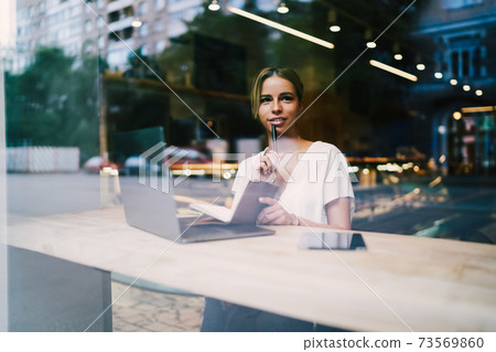 Businesswoman talking on modern telephone while working freelance at laptop computer in coffee shop. Businesswoman talking on modern telephone while working freelance at laptop computer in coffee shop. 73569860