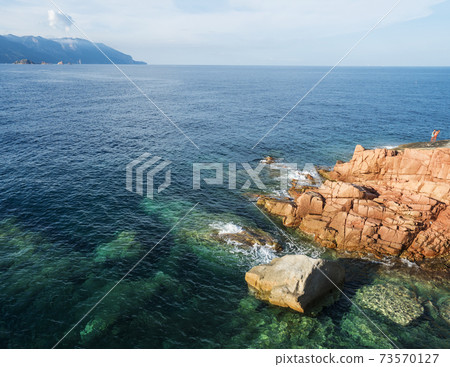 Red Rocks called Rocce Rosse at mediterranean sea coastline in Arbatax with two boys fishing. Tortoli, Ogliastra, Sardinia, Italy. Summer sunny day, golden hour 73570127
