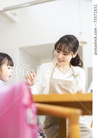 Girl and mother studying in the living room 73571831