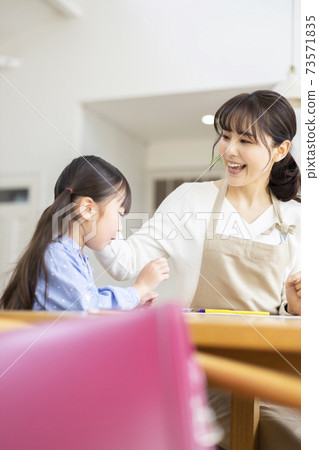 Girl and mother studying in the living room 73571835