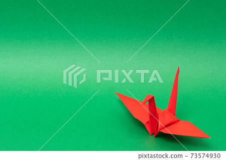 Red paper cranes on a green background 73574930