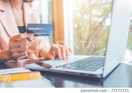 Business people holding credit cards and using laptops shopping online. 73575335