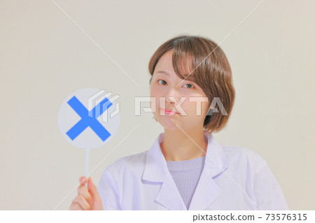 Nurse holding a plate with a ✖ sign_close-up Nurse holding a plate with a ✖ sign_close-up 73576315