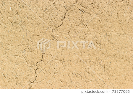 Adobe - clay and straw material weathered wall of rural old country house close-up as clay background. Adobe - clay and straw material weathered wall of rural old country house close-up as clay background. 73577065