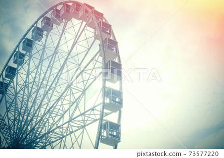 Under view of ferris wheel for background with copy space. Toned photo with sun lens flare. Under view of ferris wheel for background with copy space. Toned photo with sun lens flare. 73577220