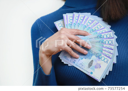 A lot of Kazakhstan money tenge in a woman hand. White background. 73577254