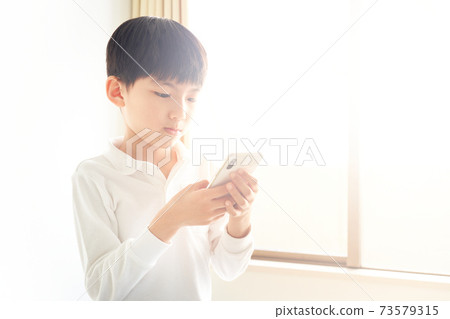 Boy staring at the screen of the smartphone Boy staring at the screen of the smartphone 73579315